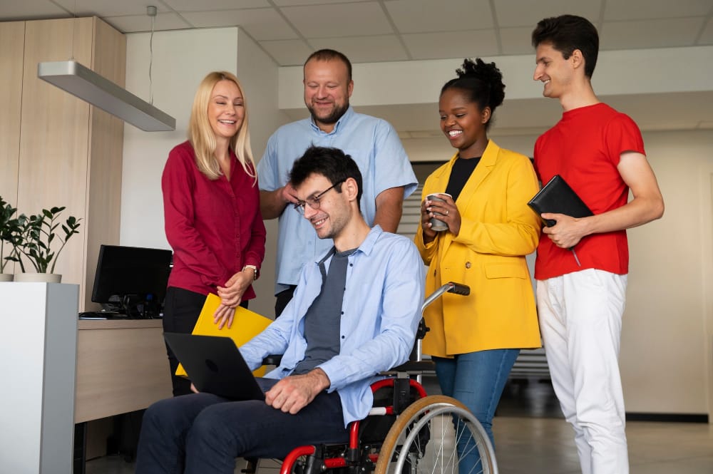 NDIS participant in a wheelchair collaborating with support team on work and life skills in an inclusive environment, promoting independence and community participation.