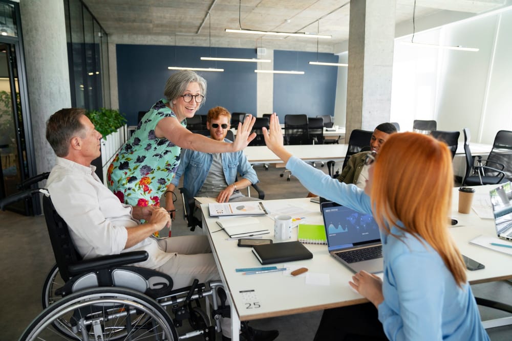 NDIS participants and support workers celebrating teamwork and community participation in an inclusive workplace setting, promoting independence, confidence, and social connection.