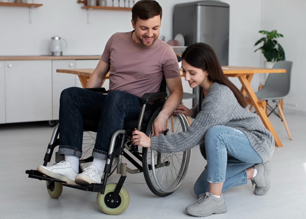 Disability support worker assisting a young man in a wheelchair with planning and daily tasks, representing NDIS life skills development and community support services.