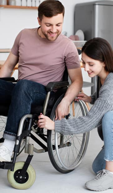 Disability support worker assisting a young man in a wheelchair with planning and daily tasks, representing NDIS life skills development and community support services.